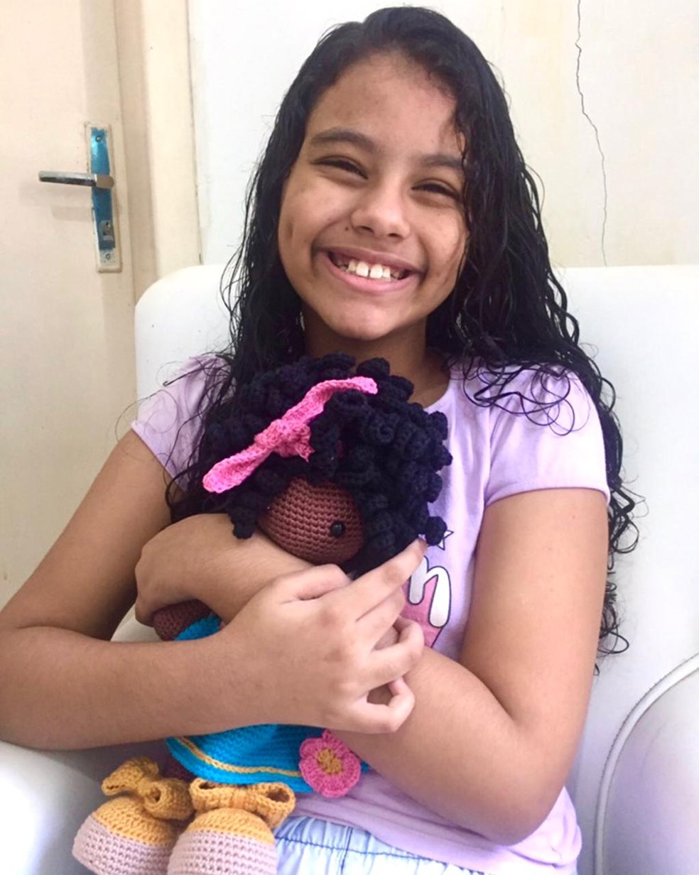 A menina ficou muito feliz com a boneca, negra e de cabelo cacheado, como ela. — Foto: Brenda de Brito/Arquivo pessoal