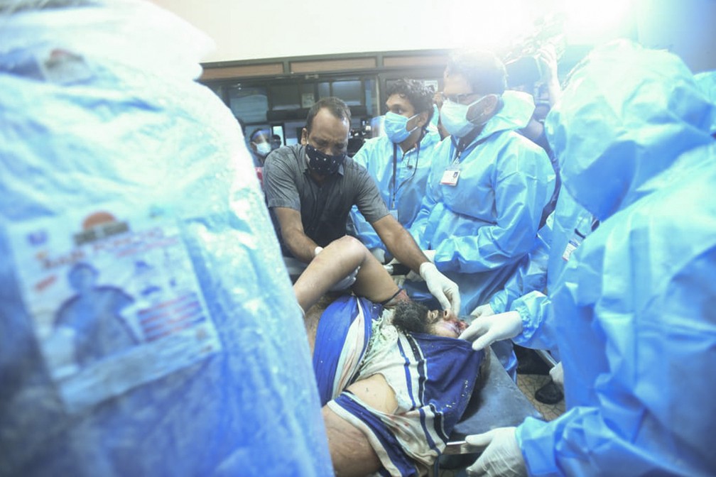 Uma das pessoas feridas após um vôo da Air India Express derrapar em uma pista durante o pouso no aeroporto de Kozhikode é levada para tratamento no Medical College Hospital — Foto: Associated Press 