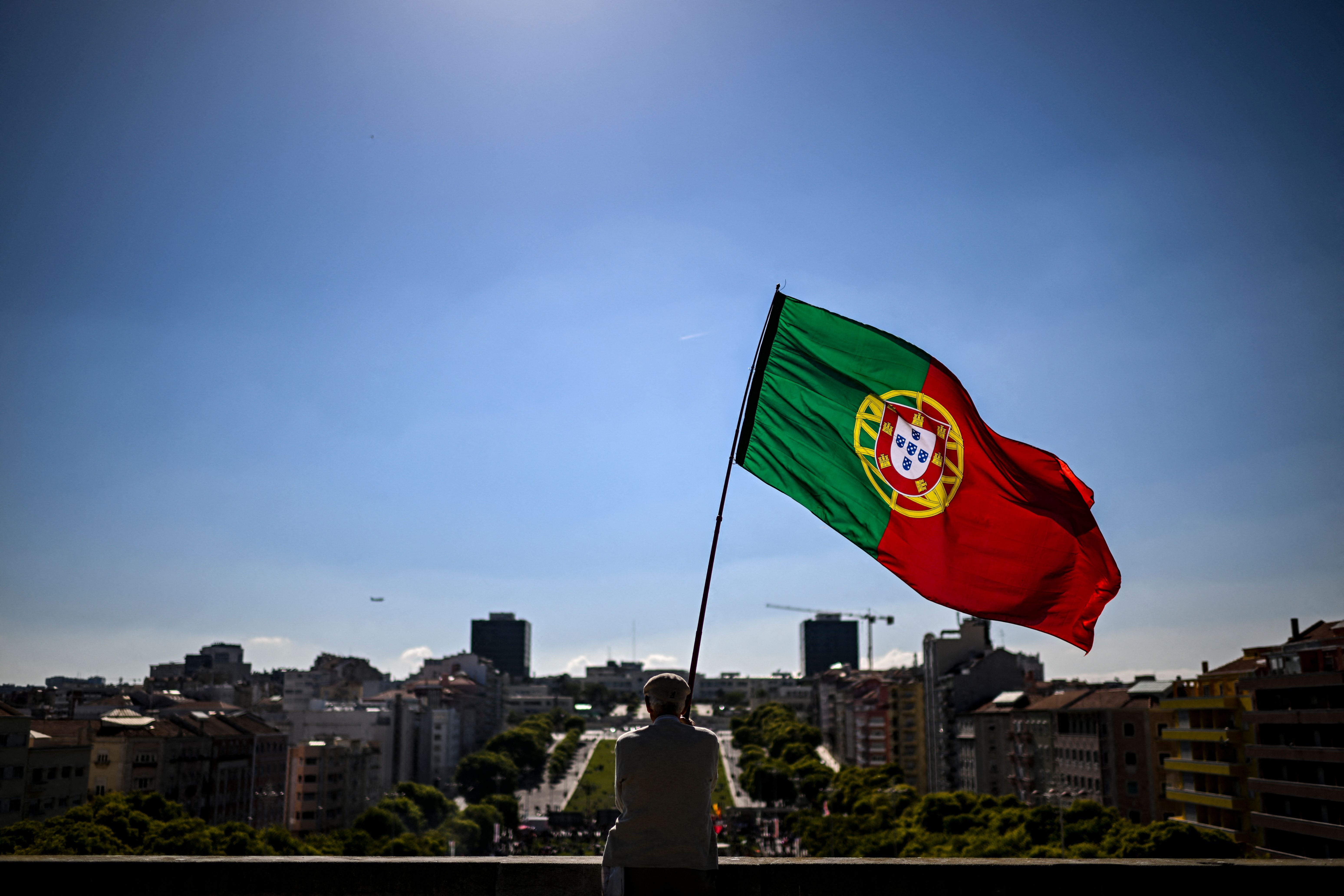 Homem segura bandeira de Portugal durante celebração do Dia do Trabalho em Lisboa