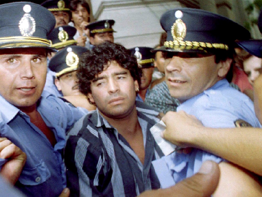 Diego Maradona é acompanhado por policiais após deixar tribunal em Mercedes, na Argentina, em março de 1994. Ele estava respondendo a processo por ter agredido jornalistas diante de sua casa dois meses antes — Foto: Reuters/Arquivo