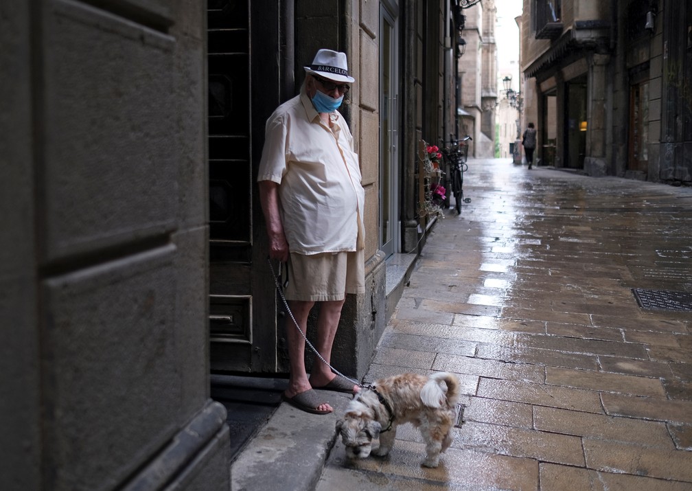 Homem passeia com seu cachorro usando uma máscara facial em Barcelona, Espanha. As autoridades regionais da Catalunha anunciaram restrições para conter a propagação do coronavírus na cidade.  — Foto: Nacho Doce / Reuters