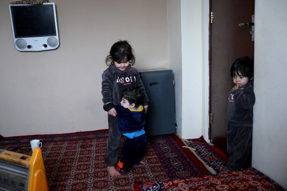Kaenat Safi, filha de Hamid Safi, brinca com o bebê Sohail Ahmadi em sua casa em Cabul — Foto: Ali Khara/Reuters
