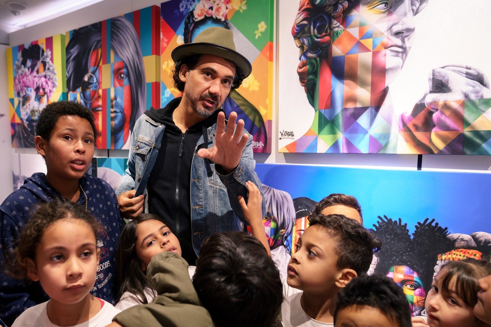 O artista Eduardo Kobra explica suas obras para crianças durante visitação em ônibus adaptado como galeria no bairro do Campo Limpo, em São Paulo — Foto: Marcelo Brandt/G1