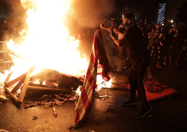 WASHINGTON, DC - MAY 31:  Demonstrators set a fire and burn a U.S. flag during a protest near the White House on May 31, 2020 in Washington, DC. Minneapolis police officer Derek Chauvin was arrested for Floyd's death and is accused of kneeling on Floyd's  (Foto: Getty Images)
