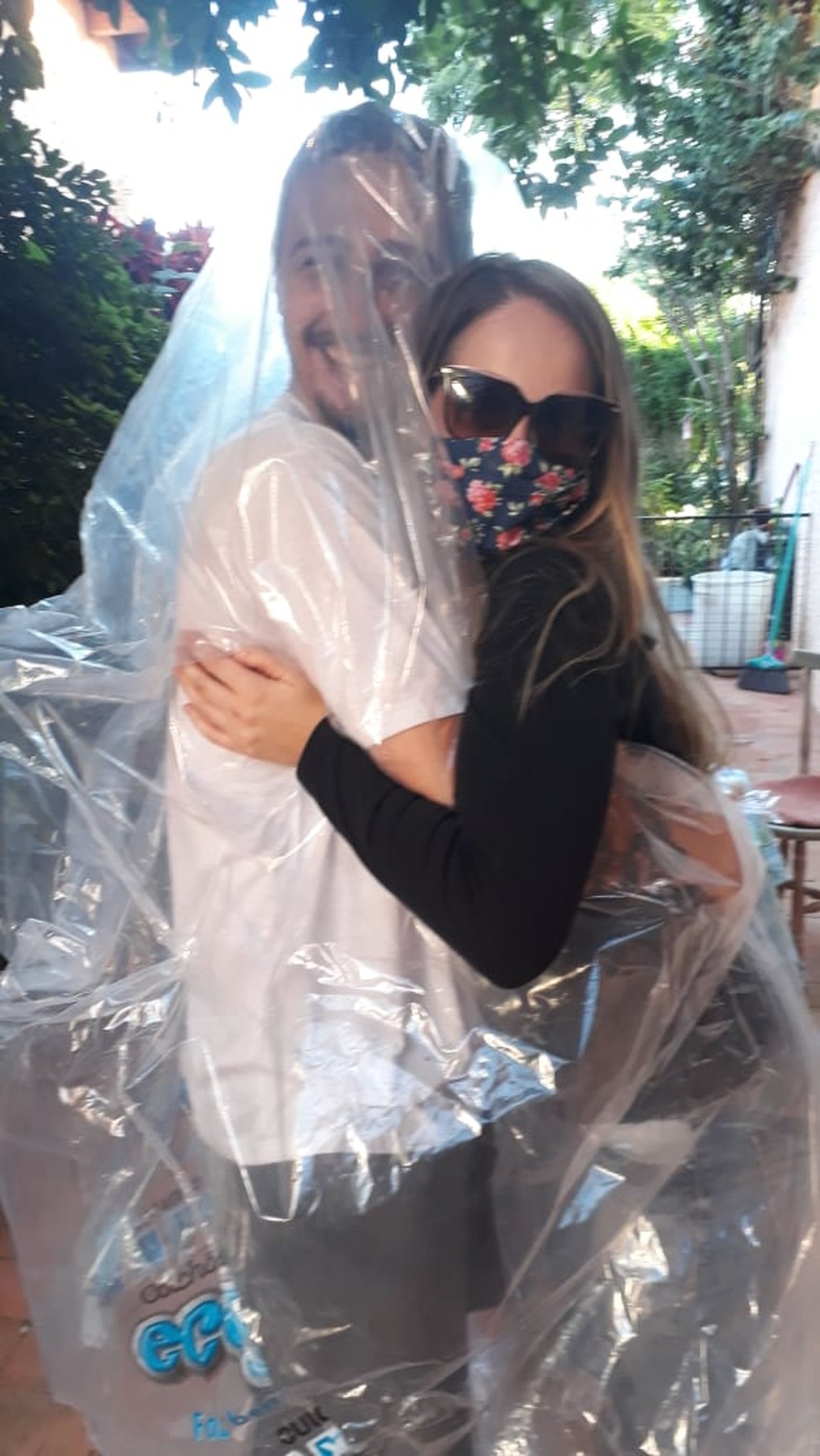 Ana Carolina abraça o irmão protegido com um saco plástico. — Foto: Arquivo pessoal