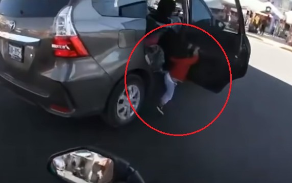 A criança ficou pendurada com as mãos na porta com o carro em movimento (Foto: Reprodução/Youtube)