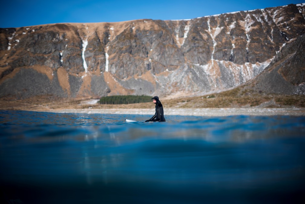 Surfista rema na praia de Unstad, no norte da Noruega, nas ilhas Lofoten do Ártico (Foto: Olivier Morin/AFP)