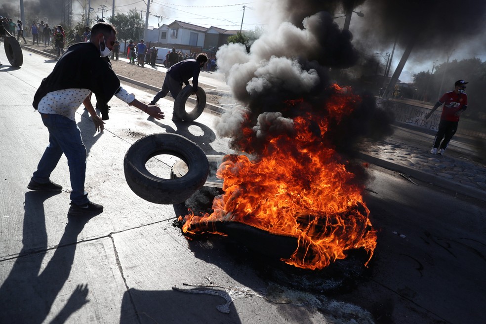 Manifestantes queimam pneus em uma barricada enquanto protestam para solicitar alimentos do governo durante quarentena geral em meio à disseminação da doença por coronavírus (Covid-19) no bairro 'Puente Alto' em Santiago, no Chile, nesta segunda (25) — Foto: Ivan Alvarado / Reuters