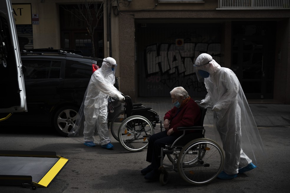 Um voluntário da ONG espanhola Open Arms empurra em cadeira de rodas um idoso residente de um lar de idosos com sintomas de coronavírus para um hospital em Barcelona, ​​Espanha. — Foto: Felipe Dana/AP