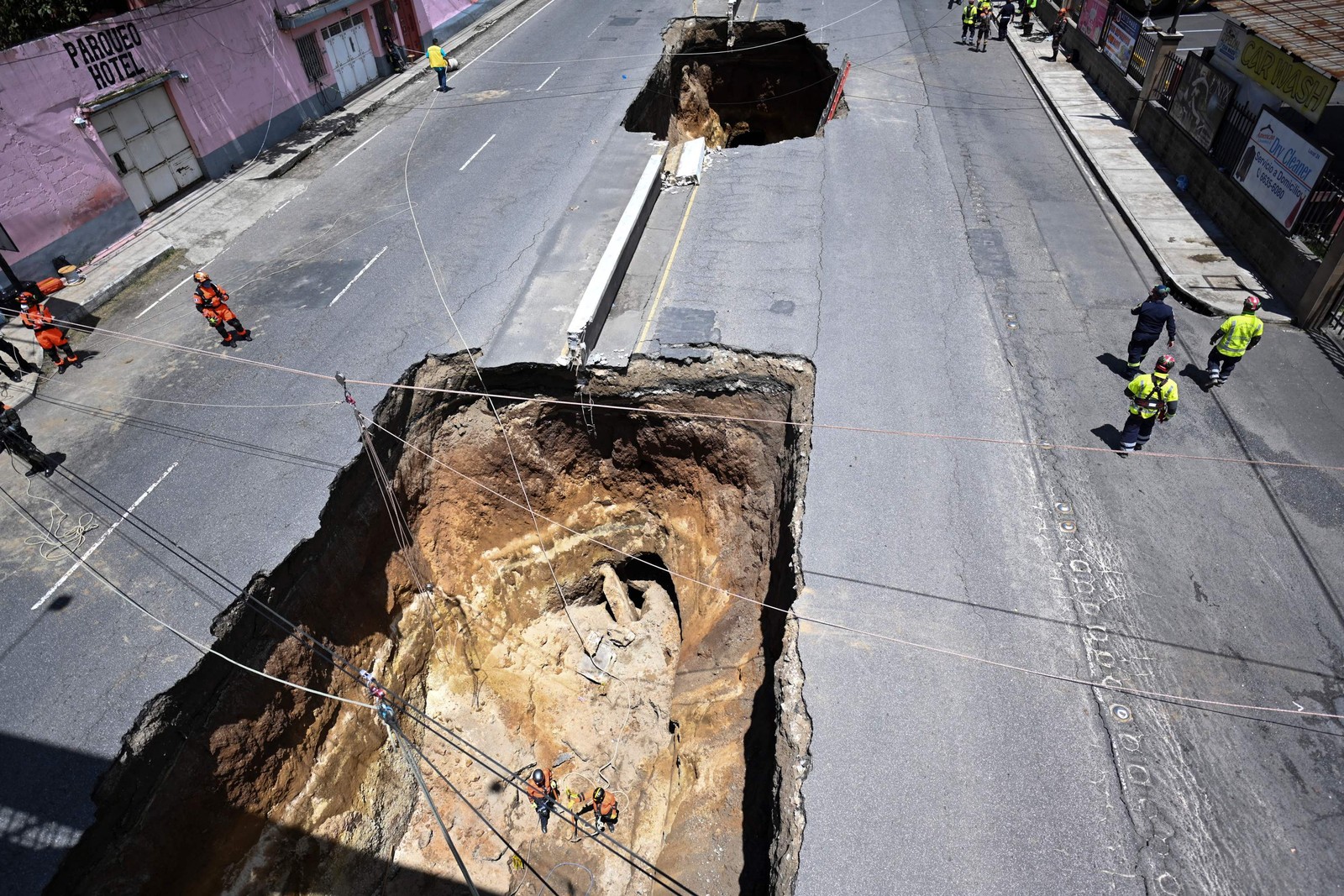 Socorristas trabalham em um buraco gigante em uma estrada, causado após às fortes chuvas que atingiram o país, em Villa Nueva, 15 km ao sul da Cidade da Guatemala — Foto: Johan ORDONEZ / AFP