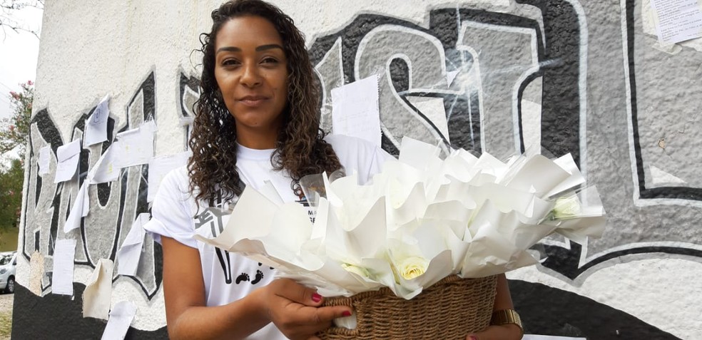Empresária Hérica Suzart percorreu mais de 50 quilômetros nesta manhã para distribuir abraços e flores na escola Raul Brasil uma semana após massacre em Suzano — Foto: Maiara Barbosa/G1