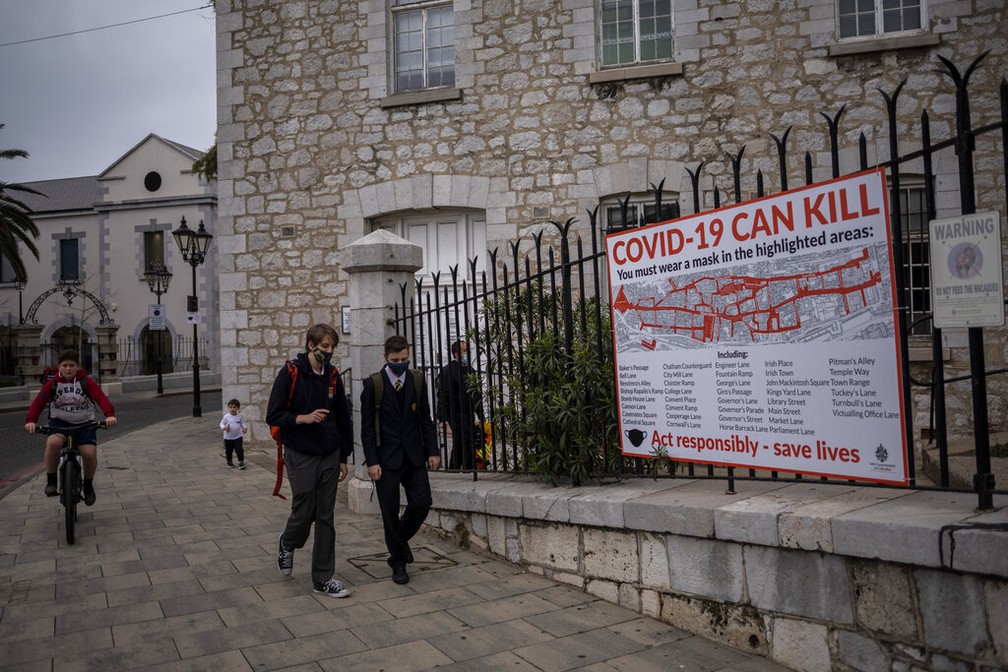 Alunos passam diante de cartaz com informação sobre a Covid-19 em Gibraltar, em foto de 4 de março de 2021 — Foto: Bernat Armangué/AP Photo