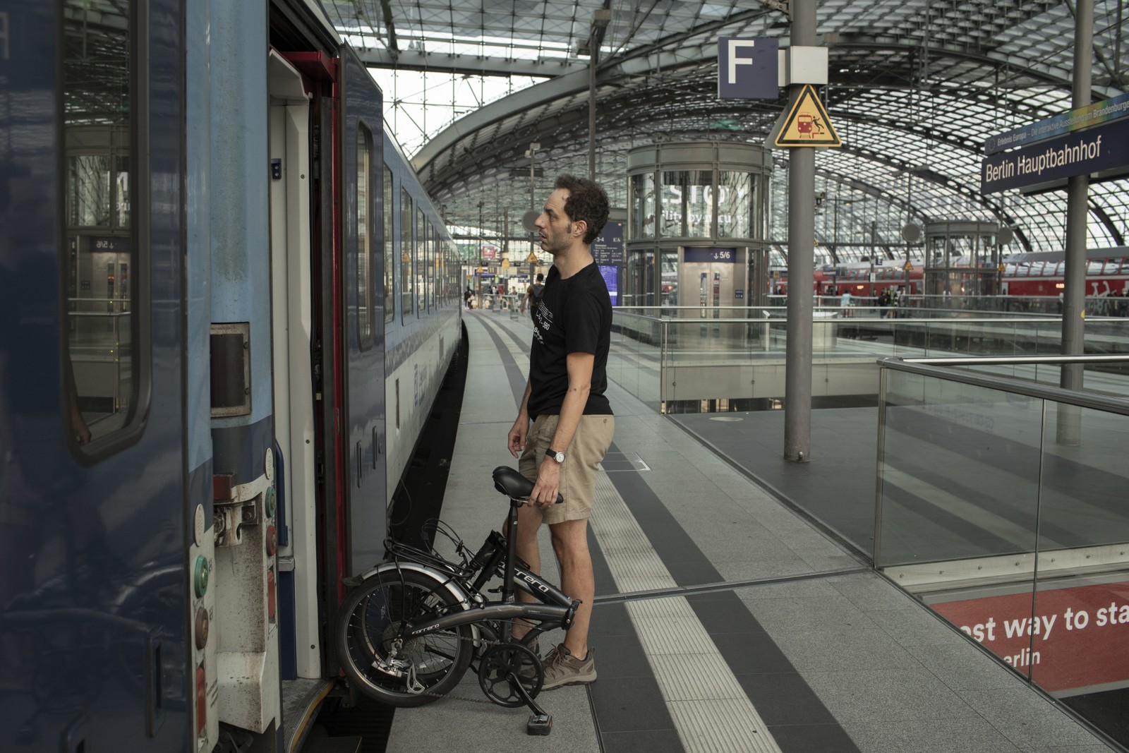 Jon Worth, com sua bicicleta dobrável, embarca em um trem com destino a Praga em Berlim — Foto: Emile Ducke/The New York Times