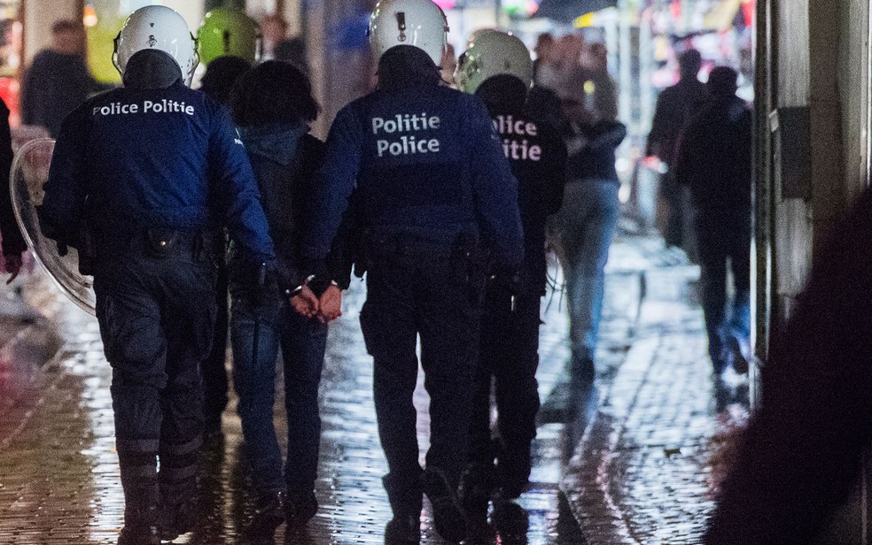 Policiais acompanham pessoa detida durante tumulto no centro de Bruxelas na quarta-feira (15) (Foto: Laurie Dieffembacq/Belga/AFP)