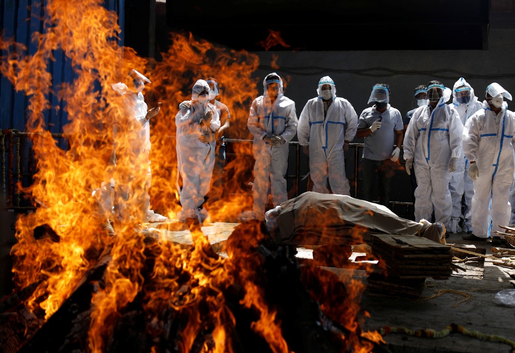 Parentes usando equipamento de proteção individual comparecem ao funeral de vítima da Covid-19 em crematório em Nova Délhi, capital da Índia, na quarta (21) — Foto: Adnan Abidi/Reuters