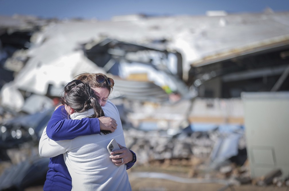 Professoras se abraçam diante dos escombros da escola onde as duas davam aulas, destruída por um tornado em Covington Tennessee (EUA) — Foto: Patrick Lantrip/Daily Memphian via AP