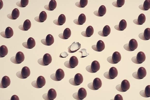 chocolate eggs placed in a pattern where one has cracked on a colored background (Foto: Getty Images)