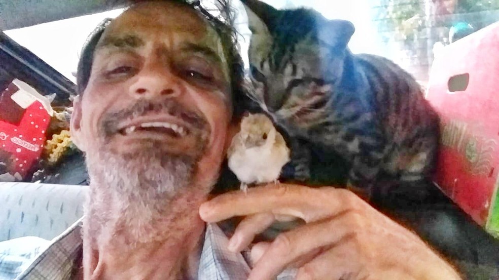 Luiz no carro onde vive com Miau, e o passarinho que também morava com eles: 'Amor pelos animais' — Foto: Arquivo pessoal