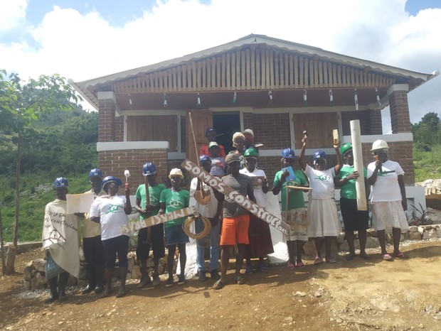 Jac-Ssone e os moradores — contrutores — do Village Marie em frente à primeira casa edificada (Foto: Arquivo pessoal)