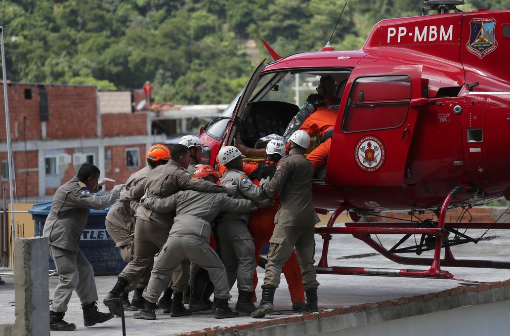 Vítima resgatada é colocada em helicóptero dos Bombeiros — Foto: REUTERS/Ricardo Moraes