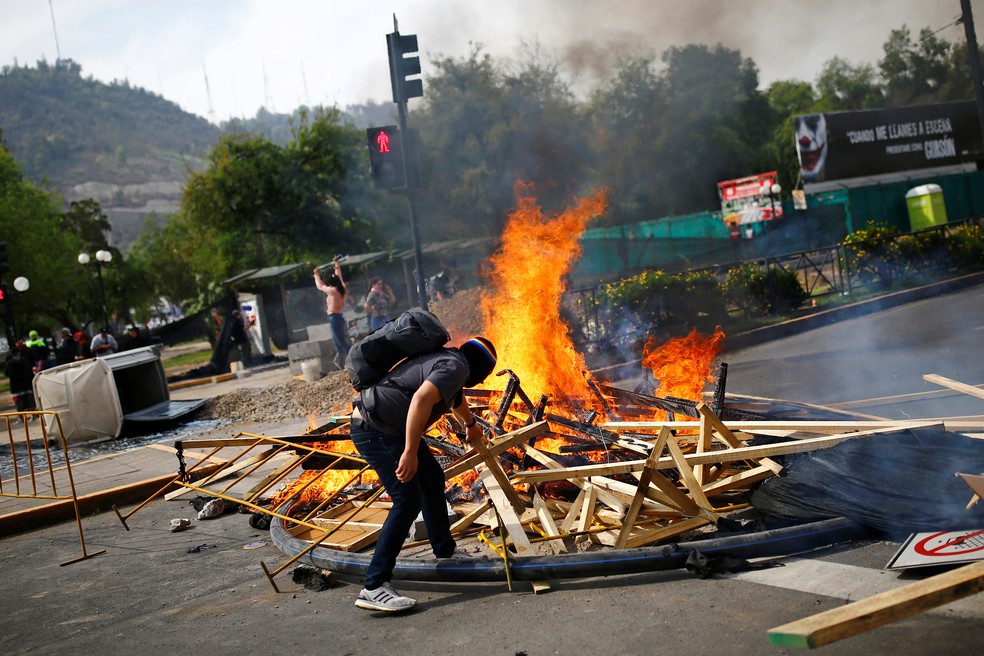 Manifestante acende uma barricada durante protesto contra o aumento da tarifa do metrô em Santiago do Chile — Foto: Edgard Garrido/Reuters