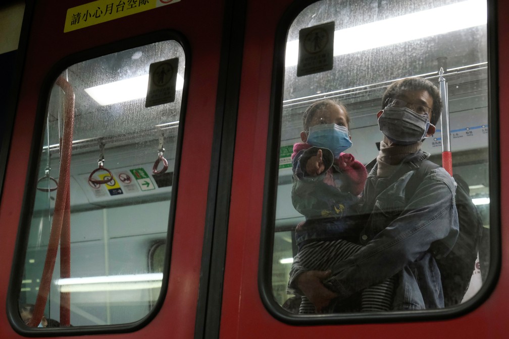 Um pai com uma criança se protege com máscaras contra o coronavírus em trem em Hong Kong nesta segunda-feira (4) — Foto: REUTERS/Tyrone Siu