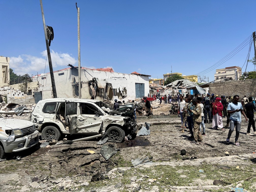 Pessoas observam veículos destruídos no local de uma explosão perto do aeroporto de Mogadíscio, capital da Somália, em 12 de janeiro de 2022 — Foto: Feisal Omar/Reuters