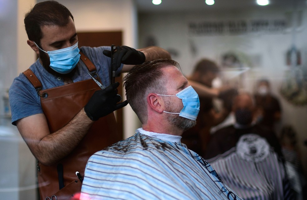 Cabeleireiro e cliente usam máscaras em Dortmund, no oeste da Alemanha, nesta segunda-feira (4)  — Foto: Ina Fassbender / AFP