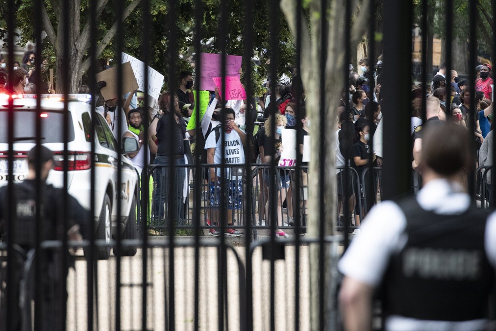 Agente do Serviço Secreto olha através de grades na Casa Branca enquanto manifestantes protestam pela morte de George Floyd em Washington DC, na sexta-feira (29). — Foto: Alex Brandon/AP