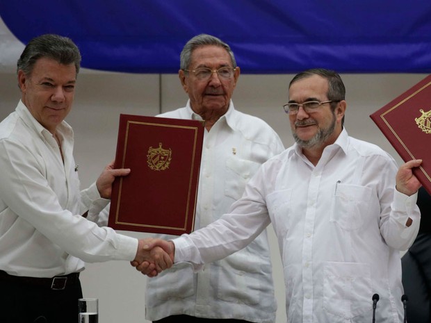 O presidente da Colômbia, Juan Manuel Santos (esq.), o presidente cubano Raúl Castro (centro) e o comandante das FARC Timoleón Jiménez (dir.) posan para fotos durante a cerimônia de assinatura do acordo de cessar-fogo bilateral definitivo em Havana  (Foto: Ramón Espinosa/AP)
