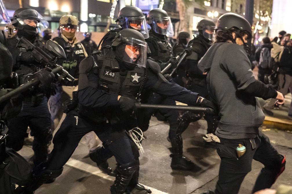 Policial de Oregon atinge manifestante com bastão enquanto dispersa multidão de manifestantes do Black Bloc em Portland — Foto: Nathan Howard/Getty Images North America/Getty Images via AFP
