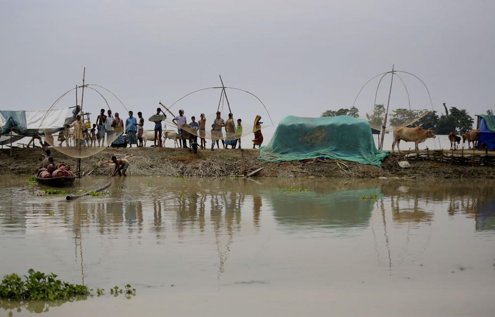 Moradores de uma vila inundada se refugiam em banco de areia no rio Brahmaputra, em 14 de julho. O governo de Assam informou neste domingo (19) que mais de 70 pessoas já morreram na região — Foto: Anupam Nath/AP