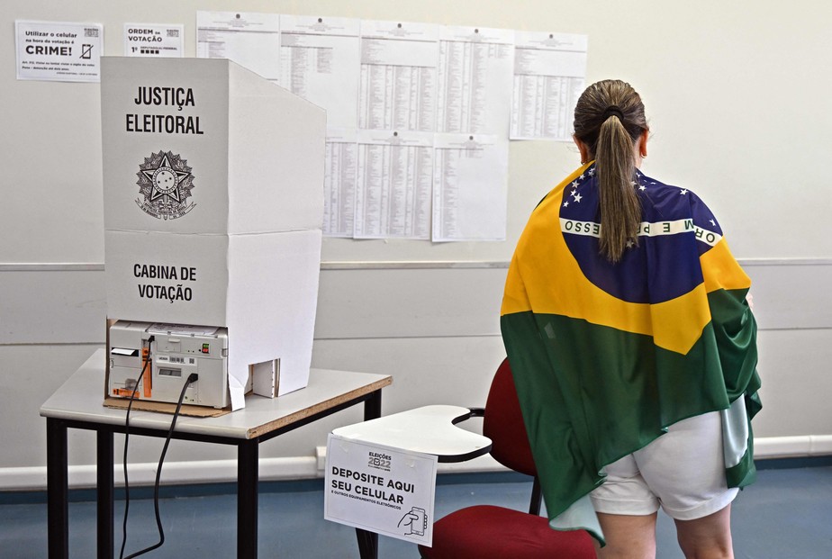 Mulher enrolada em uma bandeira do Brasil vota em Brasília.