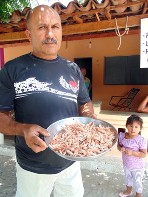Francisco Medeiros, o Titi, mostra o pouco do camarão que conseguiu pegar (Foto: Anderson Barbosa/G1)