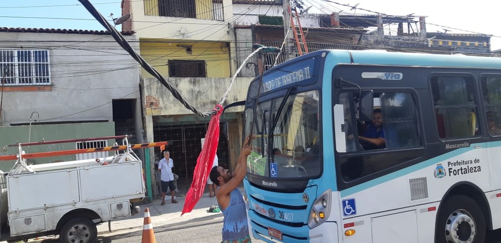 Moradores ajudaram a levantar a fiação enquanto os veículos passavam pela via em Fortaleza. — Foto: Leabém Monteiro/SVM