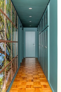 No corredor, paredes, porta e teto pintados de azul esverdeado. Projeto do escritório Triart Arquitetura