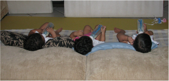 O trio, mais independente, segurando as mamadeiras (Foto: Arquivo Pessoal/ Paola Lobo)