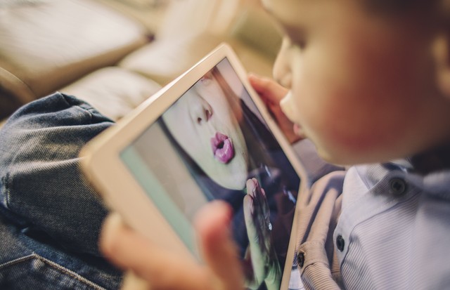 Little boy talking to his working Mother over the internet blowing her a kiss (Foto: Getty Images)