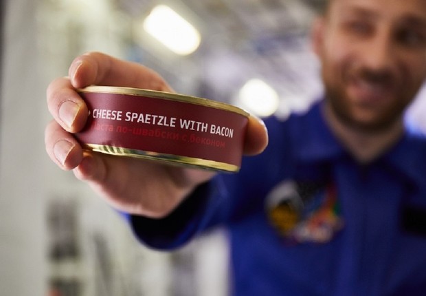 Astronauta da Alemanha com a refeição que ele vai comer na Estação Espacial Internacional - e passageiros da Lufthansa vão comer em voos de longa distância (Foto: Divulgação)