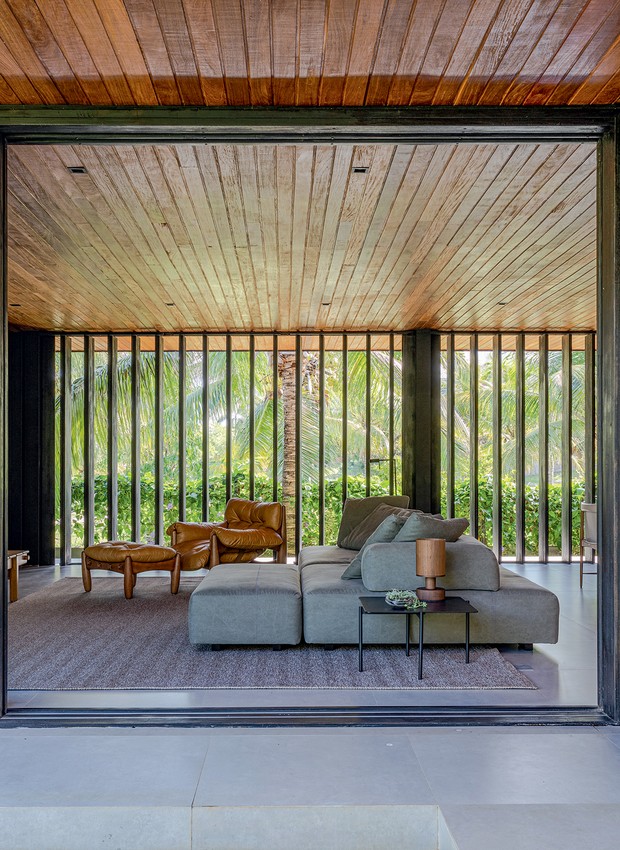 Os brisés verticais móveis de réguas de madeira carbonizada, largura 27 cm, da Demuner,  permitem a ventilação cruzada e filtram a luz solar na sala de estar (Foto: Gabriela Daltro / Divulgação)