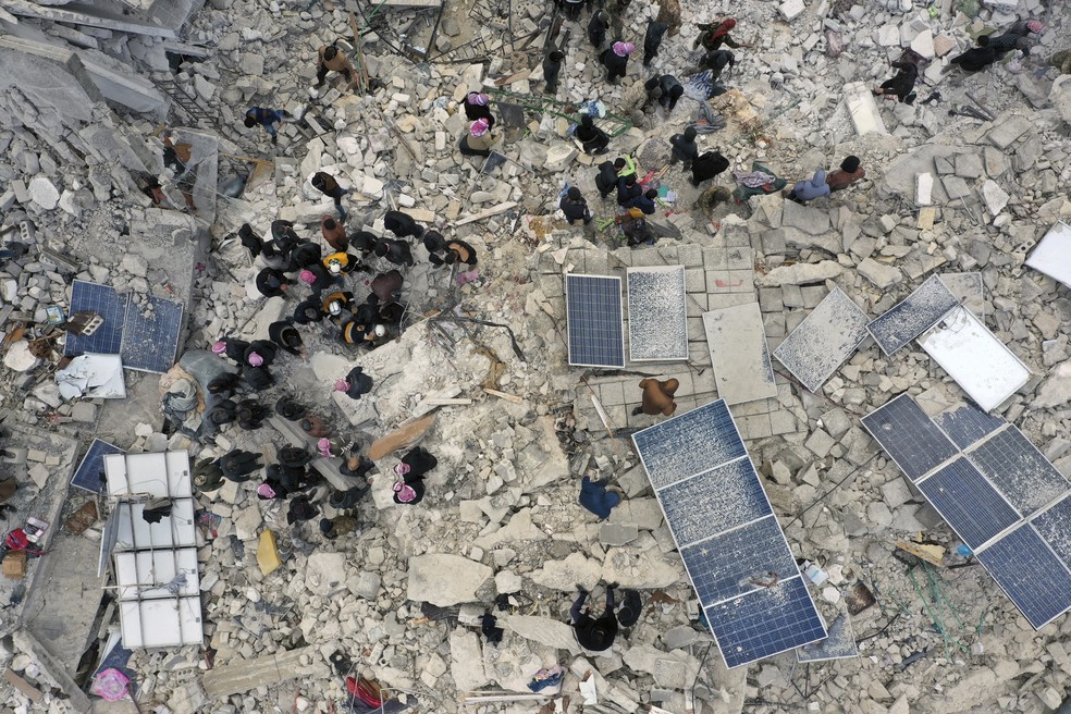 Pessoas procuram sobreviventes nos escombros de prédios destruídos na cidade de Harem, perto da fronteira com a Turquia, província de Idlib, Síria, nesta segunda-feira (2) — Foto: Ghaith Alsayed/AP