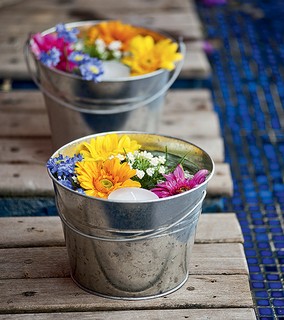 Velas e flores coloridas decoram estes vasinhos de metal