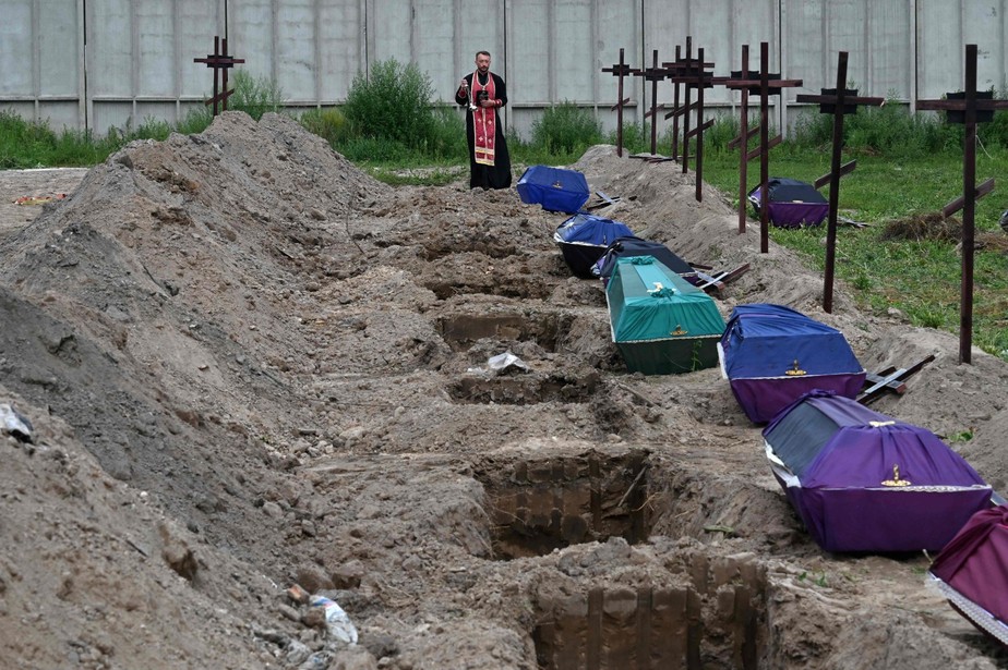 Padre faz oração antes de sepultamento de corpos não identificados em Bucha, na Ucrânia