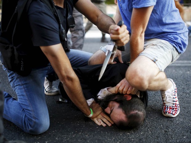 Pessoas desarmam o judeu ultraortodoxo que atacou participantes da parada gay com uma faca em Jerusalém, Israel. Seis pessoas ficaram feridas no ataque (Foto: Amir Cohen/Reuters)