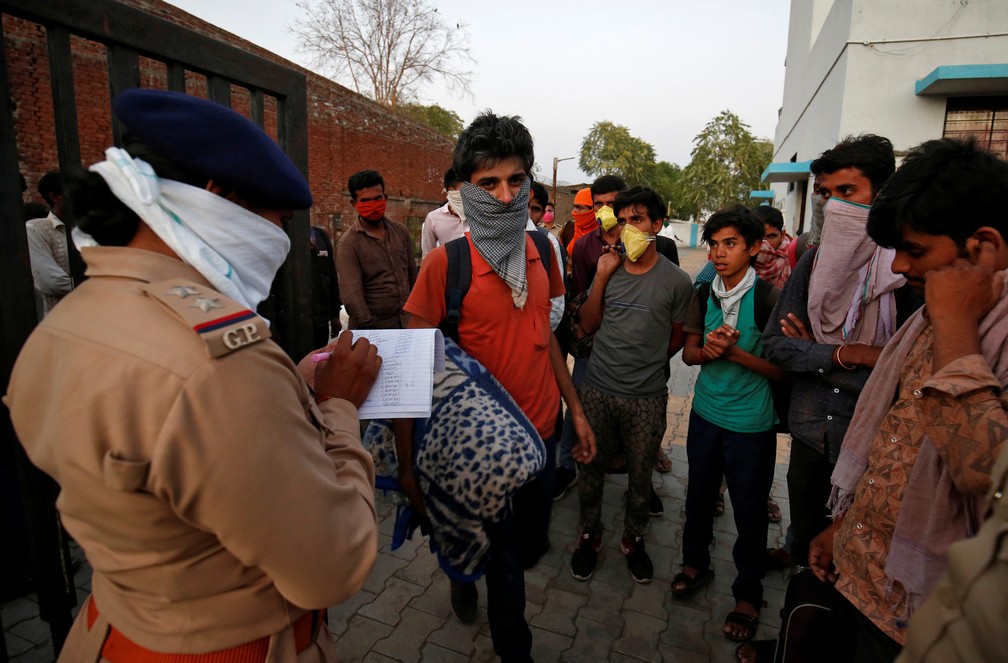31 de março: policial anota informações de trabalhadores migrantes que foram transferidos para abrigo durante quarentena nacional de 21 dias decretada pelo governo, em Ahmedabad, na Índia. — Foto: Amit Dave/Reuters