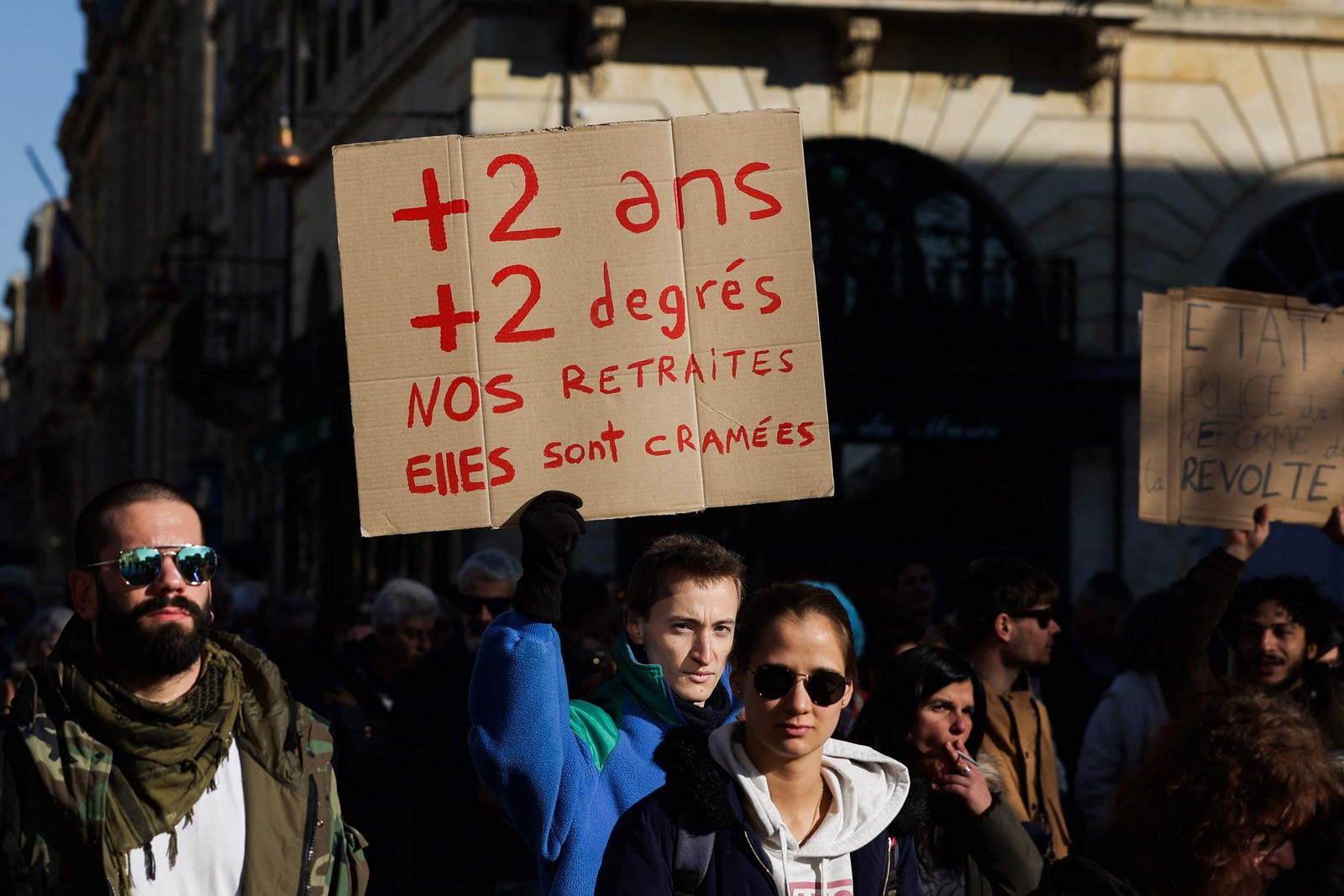 Cartaz com os dizeres "mais dois anos, mais dois diplomas, nossas pensões estão sendo queimadas" é levantado durante o protesto — Foto: Thibaud Moritz/AFP