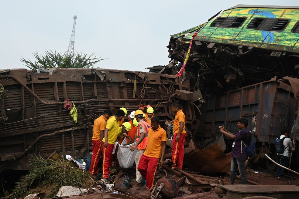 Trabalhadores carregam o corpo de uma das vítimas no local do acidente entre trens no estado oriental de Odisha — Foto: DIBYANGSHU SARKAR / AFP