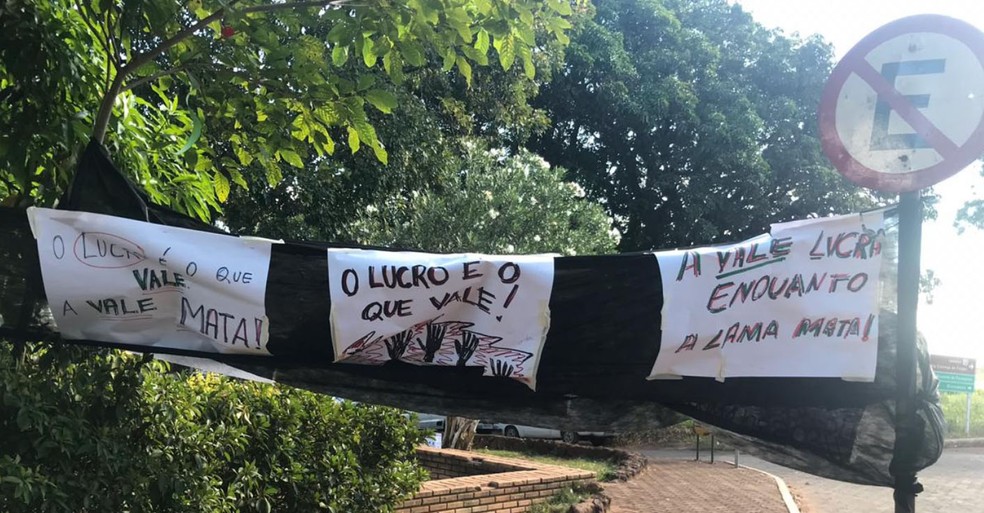 Cartazes de protesto contra mineradora são colocados perto de área devastada pela lama — Foto: Henrique Coelho/G1