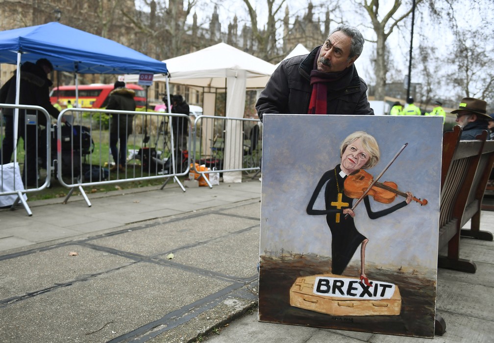 Após derrota do acordo do Brexit no Parlamento britânico, homem mostra pintura de Theresa May 'enterrando' o Brexit — Foto: Clodagh Kilcoyne/Reuters