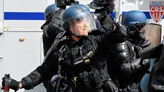 Policial francês lança uma granada de gás lacrimogêneo contra manifestantes durante protesto em Rennes — Foto: Damien MEYER / AFP